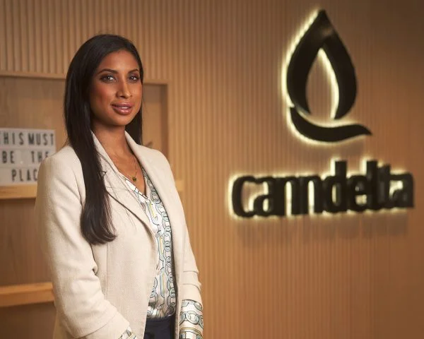 CEO and Co-Founder of Canndelta, Sherry Boodram. Standing next to the company logo that reads Canndelta.