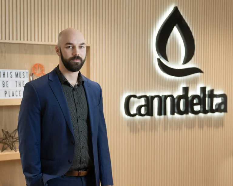 Image of Jason Goble standing in front of the CannDelta Logo