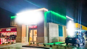 Outside of a cannabis dispensary at night with green accent lighting around the front-top and side of the building