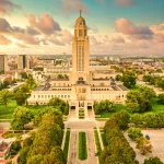 Aerial view of the Nebraska State Capitol in Lincoln with the city skyline in the background during a colorful sunset.