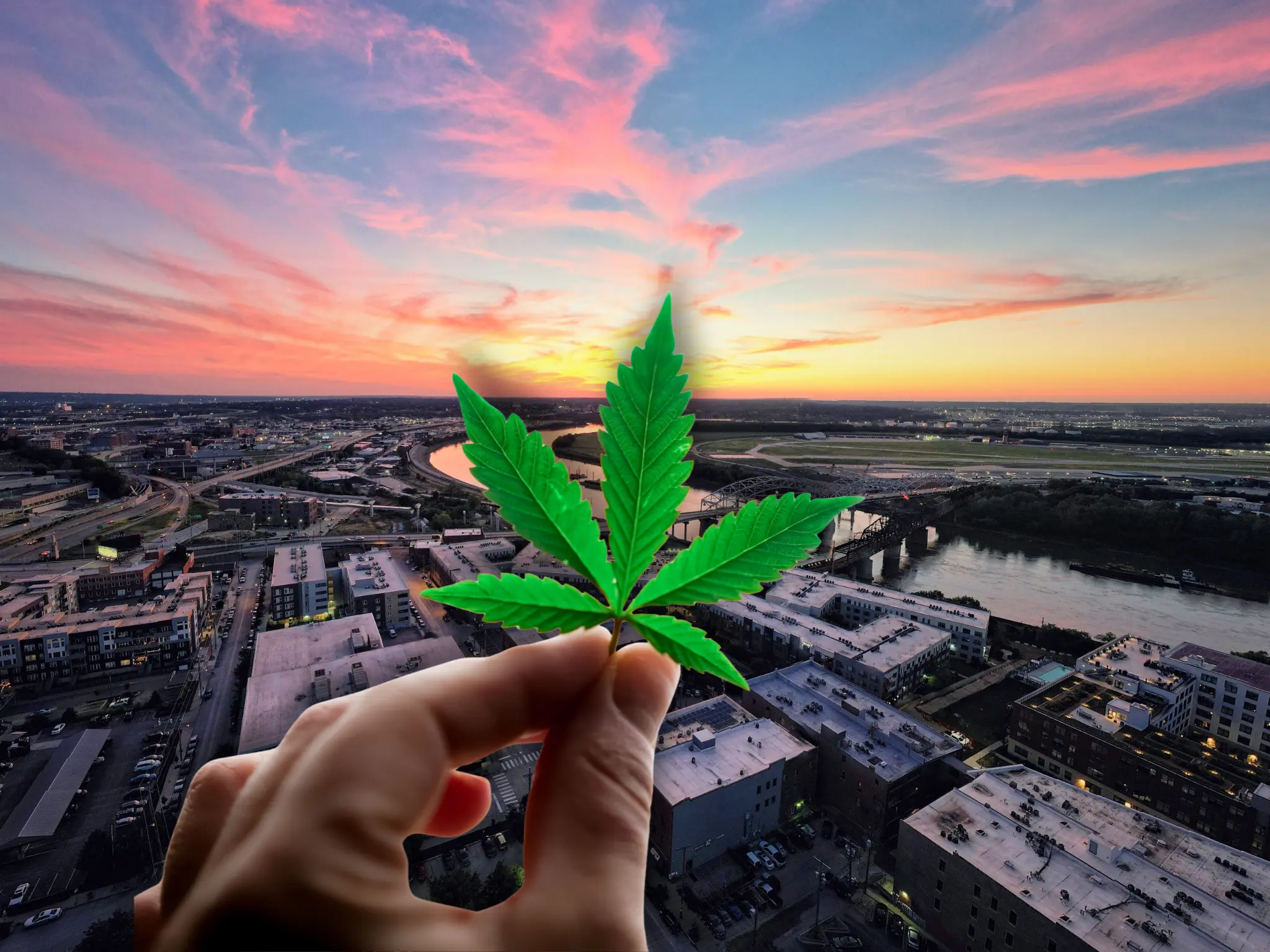 Hand holding a cannabis leaf over a Missouri cityscape at sunset, representing the state's cannabis industry regulations.